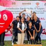 Equipo junto a la botarga de corazón frente a la lona del rally de la Jurisdicción Sanitaria No. II Tuxpan.
