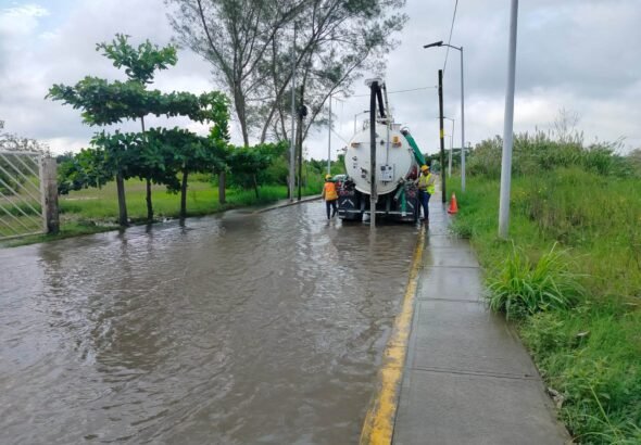 Camión con equipo Vactor y personal de Agua y Saneamiento realizando trabajos de desazolve en una calle inundada de Tuxpan.
