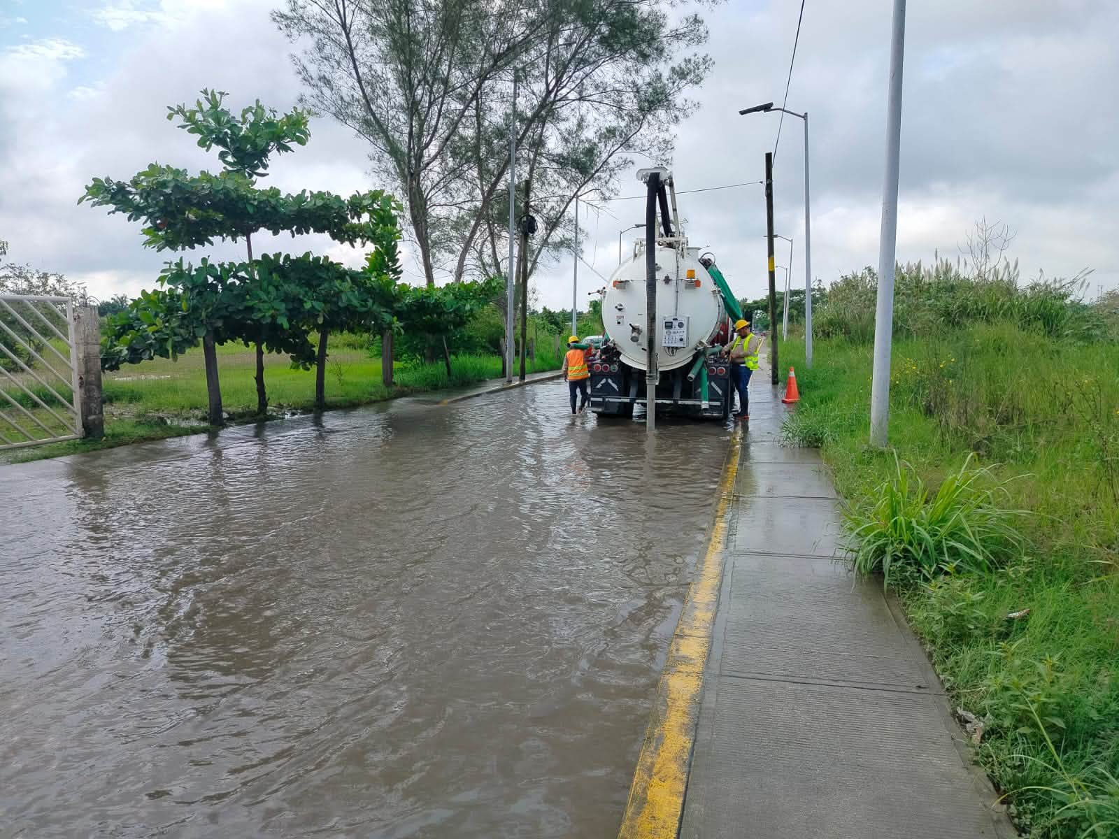 Camión con equipo Vactor y personal de Agua y Saneamiento realizando trabajos de desazolve en una calle inundada de Tuxpan.